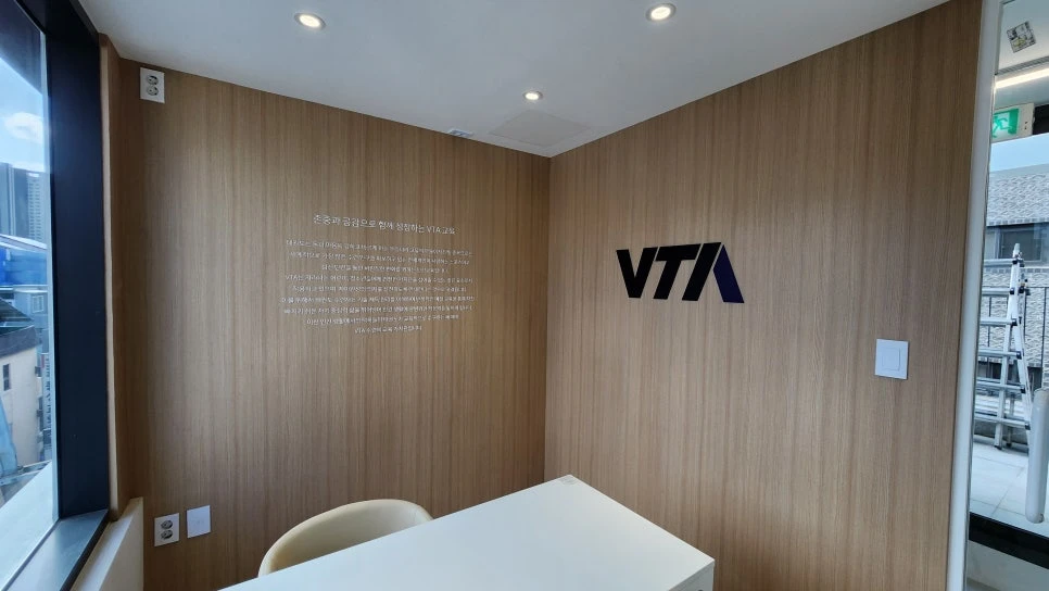 VTA 5층 상담실의 우드 벽면 로고와 상담 테이블