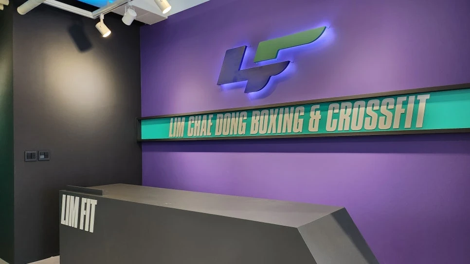 바이올렛 벽면에 후광 조명으로 설치한 LIMFIT 복싱 로고 사인