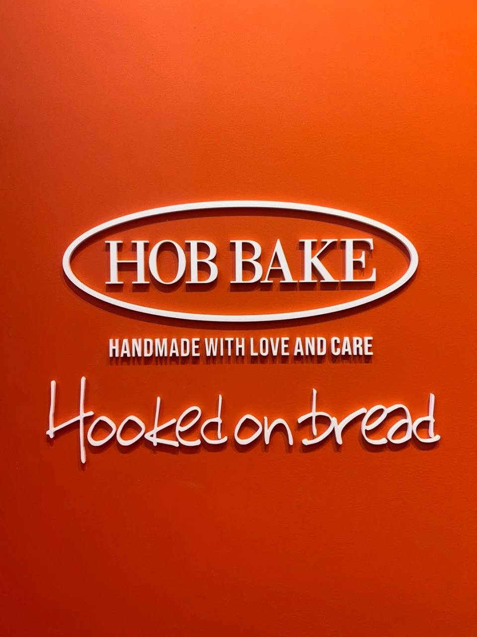레드 벽면에 설치한 HOB BAKE 입체 로고와 Hooked on bread 사인